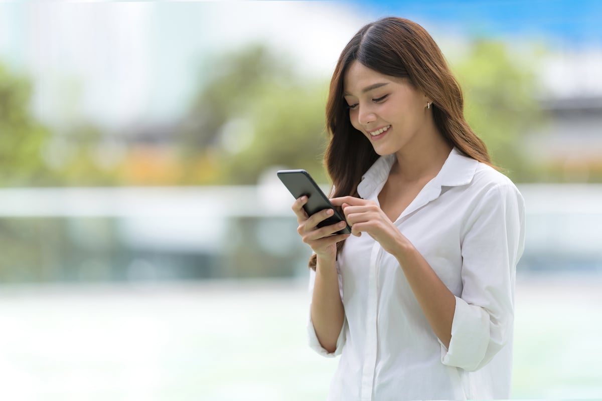 Outdoors Portrait of Happy Young Woman Using a Phone